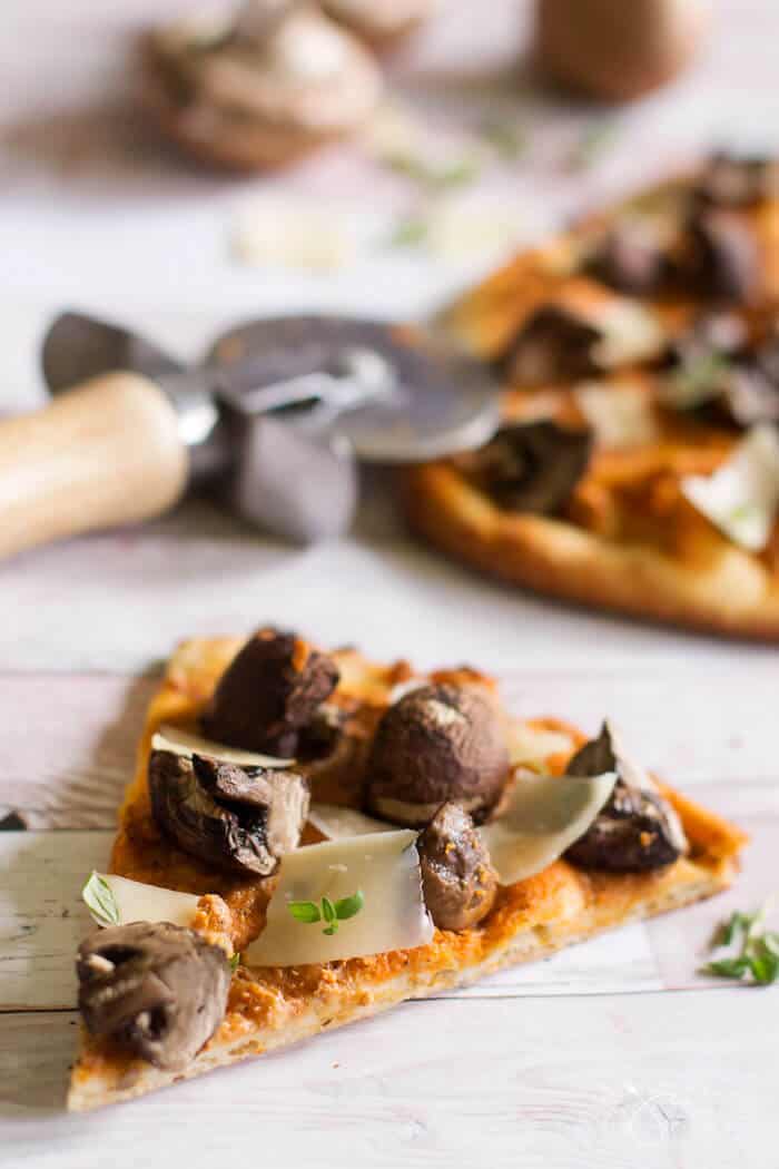 A slice of naan flatbread pizza with goat cheese and portobello mushrooms